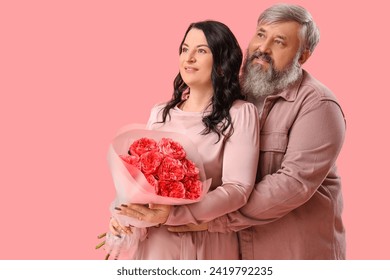 Beautiful mature couple with bouquet of roses hugging on pink background. Valentine's Day celebration - Powered by Shutterstock