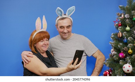 A Beautiful Mature Couple Making A Video Call On Christmas Day. Grandparents Holding A Smartphone To Say Hello To Her Family Away From Home.