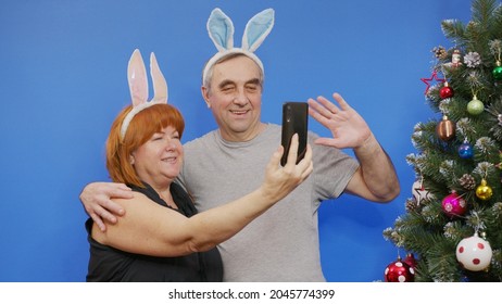 A Beautiful Mature Couple Making A Video Call On Christmas Day. Grandparents Holding A Smartphone To Say Hello To Her Family Away From Home.