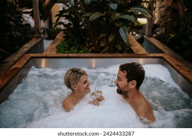 Beautiful mature couple relaxing in hot tub, drinking champagne, enjoying romantic wellness weekend in spa. Concept of Valentine's Day. - Powered by Shutterstock