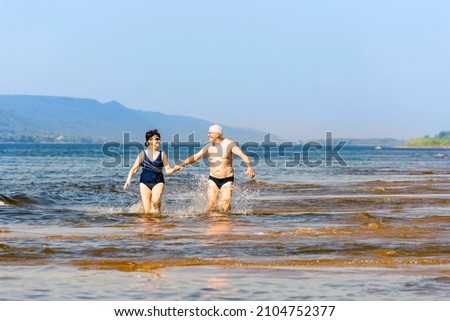 beautiful mature couple runs on the water along the wild beach on a hot summer day