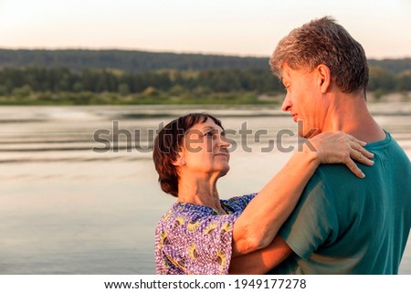 Beautiful mature couples dance on a wild beach in the rays of the setting sun on a summer evening