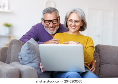 Beautiful Mature Family Couple Looking At Laptop With Smile On Face While Spending Great Time Together At Home On Retirement, Happy Retired Husband And Wife Watching Funny Video On Computer