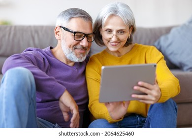 Beautiful Mature Family Couple Looking At Tablet With Smile On Face While Spending Great Time Together At Home On Retirement, Happy Retired Husband And Wife Watching Funny Video On Computer