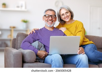 Beautiful mature family couple looking at laptop with smile on face while spending great time together at home on retirement, happy retired husband and wife watching funny video on computer - Powered by Shutterstock