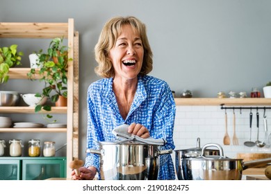 Beautiful mature senior woman at home, domestic life and leisure moments - 50-60 years old pretty female adult cooking lunch in the kitchen - Shutterstock ID 2190182475