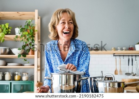 Beautiful mature senior woman at home, domestic life and leisure moments - 50-60 years old pretty female adult cooking lunch in the kitchen