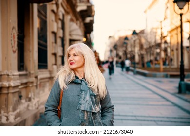 Beautiful Mature Stylish Woman With White Long Hair Walking In The City Street. Copy Space 