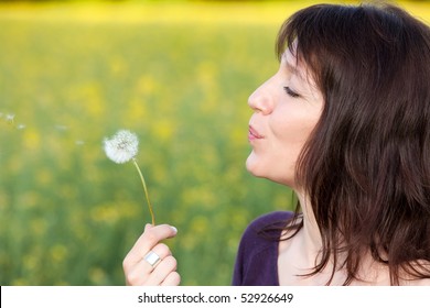 Beautiful Mature Woman Blowing Dandelion Seeds