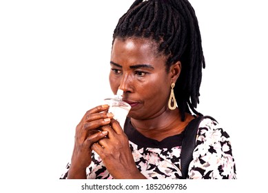 A Beautiful Mature Woman With Braids Standing Over White Background Smelling Perfume.