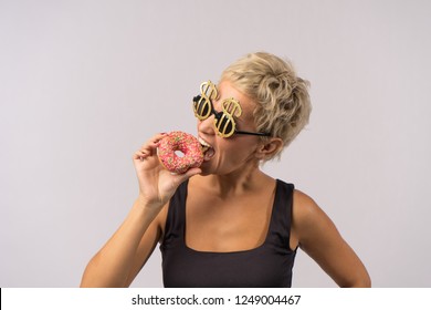 A Beautiful Mature Woman Is Eating Bright Donut.