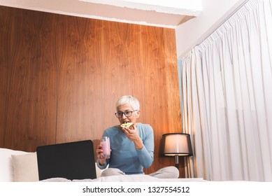 Beautiful Mature Woman Eating Healthy Snack And Realaxing At Her Bedroom By Watching Movie On Her Laptop, Weekend Vibes And Free Time Concept