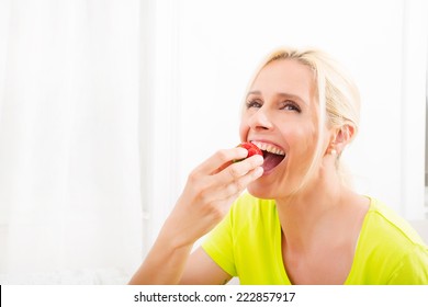 A Beautiful Mature Woman Eating Strawberry At Home. 