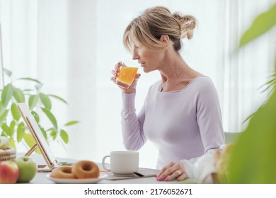 Beautiful Mature Woman Having A Relaxing Breakfast At Home, She Is Drinking Fresh Orange Juice