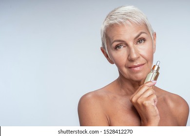 Beautiful Mature Woman Holding Face Serum In Her Hand