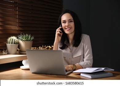 Beautiful mature woman with laptop talking on smartphone at home - Shutterstock ID 1683580615