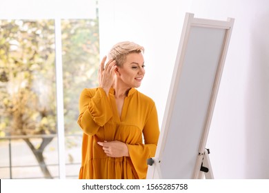 Beautiful Mature Woman Looking At Herself In Large Mirror Indoors