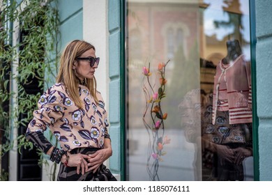 Beautiful Mature Woman Outside The Store Looking At New Fashionable Clothes In Window. Older Woman Shopping.