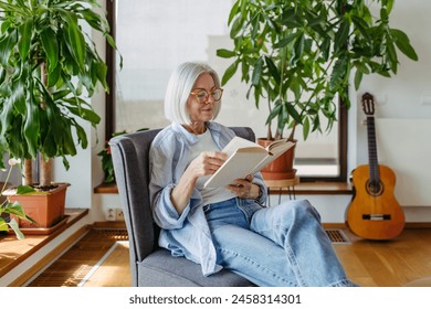 Beautiful mature woman reading book, feeling cozy and happy. Weekend activity for older woman, relaxing at home. - Powered by Shutterstock