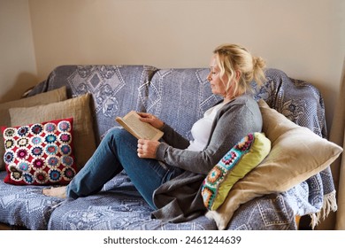 Beautiful mature woman reading book, feeling cozy and happy. Weekend activity for older woman, relaxing at home. - Powered by Shutterstock