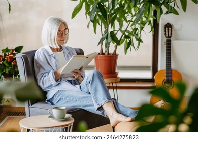 Beautiful mature woman reading book, feeling cozy and happy. Weekend activity for older woman, relaxing at home. - Powered by Shutterstock