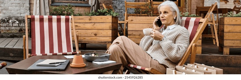 A beautiful mature woman relaxes in a casual chair, sipping coffee and engaged in conversation. - Powered by Shutterstock