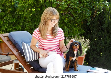 Beautiful Mature Woman Sitting In Garden With Her Spaniel Puppy. 