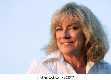 A beautiful, mature woman smiling confidently into the late afternoon sun.