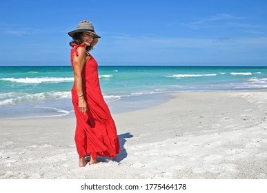 Beautiful Mature Woman Wearing a Red Summer Dress on the Beach