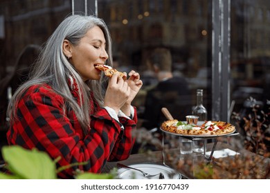 Beautiful matured asian woman is eating pizza in cafe terace