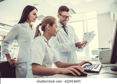 Beautiful Medical Doctors Are Using A Computer, Studying Test Results And Smiling While Working At The Lab