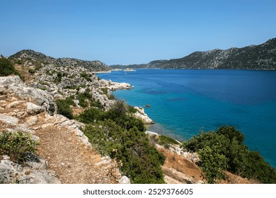 A beautiful Mediterranean coastal landscape with clear blue waters, rocky cliffs, and green hills,  - Powered by Shutterstock