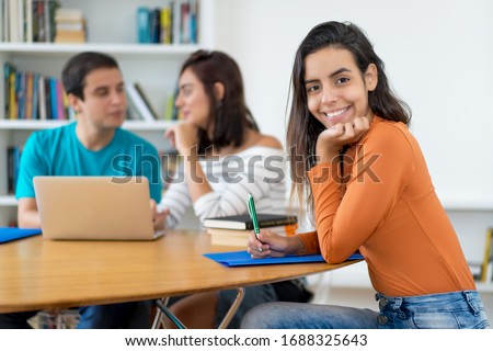 Beautiful mexican female student with group of computer science students at classroom of university