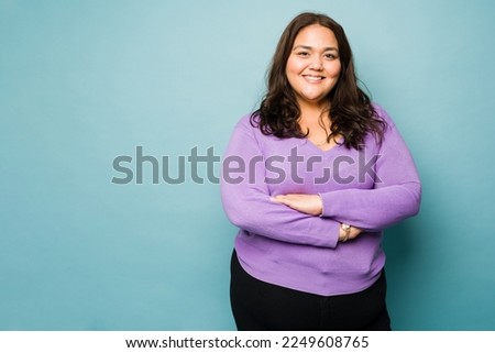 Beautiful mexican obese woman with her arms crossed smiling against a studio background with copy space