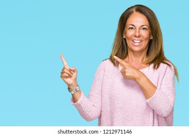 Beautiful middle age adult woman wearing winter sweater over isolated background smiling and looking at the camera pointing with two hands and fingers to the side. - Shutterstock ID 1212971146