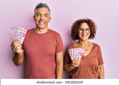 Beautiful Middle Age Couple Holding 50 Mexican Pesos Banknotes Looking Positive And Happy Standing And Smiling With A Confident Smile Showing Teeth 