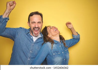 Beautiful Middle Age Couple Together Standing Over Isolated Yellow Background Dancing Happy And Cheerful, Smiling Moving Casual And Confident Listening To Music