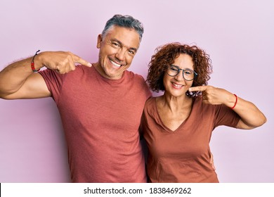Beautiful middle age couple together wearing casual clothes smiling cheerful showing and pointing with fingers teeth and mouth. dental health concept. 