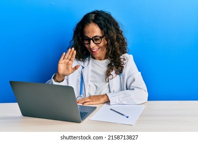 Beautiful Middle Age Doctor Woman Doing Video Call Waving To Laptop Smiling With A Happy And Cool Smile On Face. Showing Teeth. 