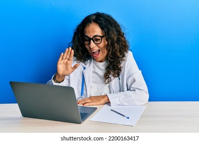 Beautiful Middle Age Doctor Woman Doing Video Call Waving To Laptop Smiling And Laughing Hard Out Loud Because Funny Crazy Joke. 