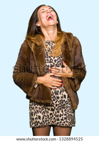 Beautiful middle age elegant woman wearing mink coat Smiling and laughing hard out loud because funny crazy joke. Happy expression.