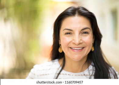 Beautiful middle age Hispanic woman smiling outside.