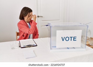 Beautiful Middle Age Hispanic Woman At Political Election Sitting By Ballot Tired Rubbing Nose And Eyes Feeling Fatigue And Headache. Stress And Frustration Concept. 