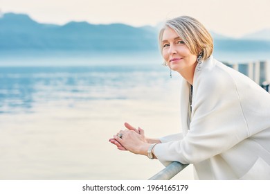Beautiful middle age woman admiring amazing view of winter lake and mountains