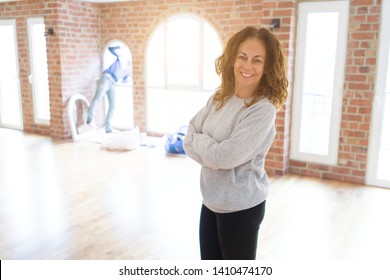 Beautiful Middle Age Woman With Curly Hair Smiling Confident At New Home, Renovating And Painting House