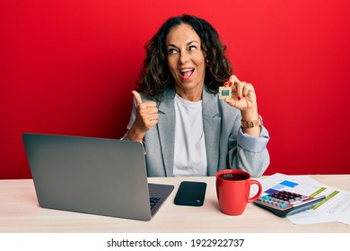 Beautiful Middle Age Woman Holding Cpu Computer Processor Pointing Thumb Up To The Side Smiling Happy With Open Mouth 