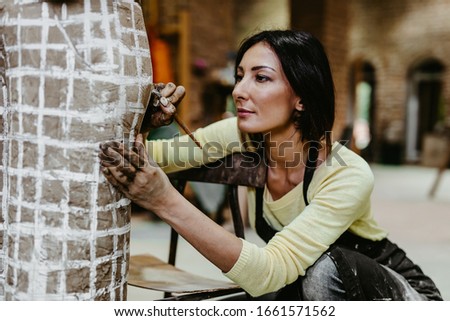 Beautiful middle age woman professional sculptor working on gorgeous sculpture.