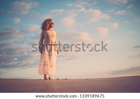 beautiful middle age young woman 40 years old enjoy the sun on her face and her body. vacation and summer leisure activity concept, sky and clouds background. caucasian people outdoors