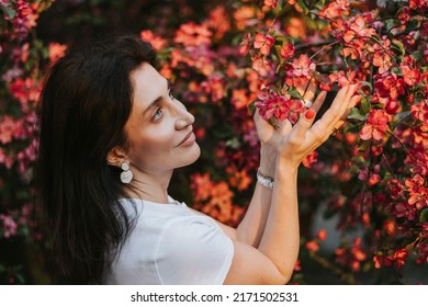 beautiful middle aged armenian woman poses in an apple blossoming pink garden, portrait in a spring park among flowering blooming trees, summer golden hour