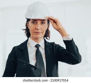 Beautiful Middle Aged Businesswoman Wears Black Suit And Tie Looking At Camera. Portrait Of Female Director CEO Team Leader With Safety Hat On White Background. Coaching And Mentoring Business Concept